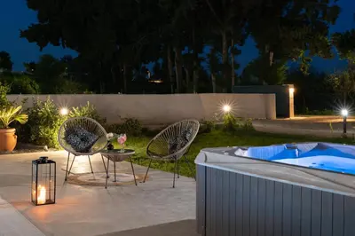 a patio with two chairs and a hot tub at night at Ethria Pool Villa with heated jacuzzi in Afantou