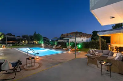 a backyard with a swimming pool at night at Ethria Pool Villa with heated jacuzzi in Afantou