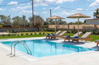 a swimming pool with two lounge chairs and a resort at Ethria Pool Villa with heated jacuzzi in Afantou