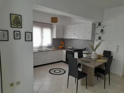 a kitchen with a table and chairs and a kitchen with white cabinets at Giotouli Apartment in Afantou