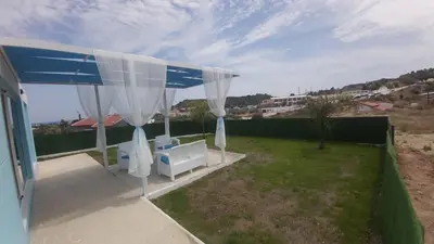a patio with a blue and white canopy and chairs at GR House Eleftheria in Afantou