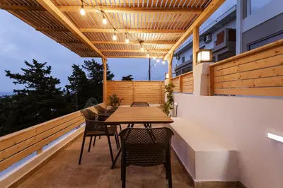 a patio with a wooden table and chairs on a balcony at Sevasti Seaview Suite in Koskinou