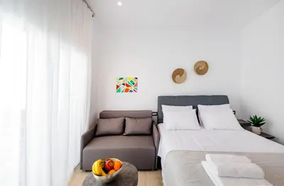 a bedroom with a bed and a couch and a bowl of fruit at Sunwaves Beach studio I in Ialyssos