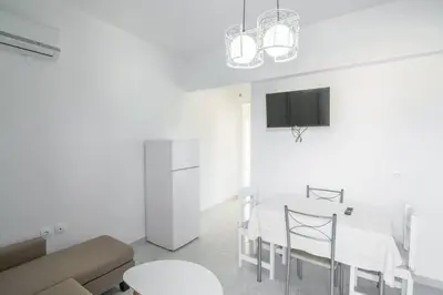 a white living room with a table and a tv at Fotis House 2 in Afantou