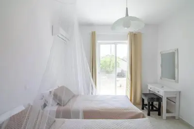 a white bedroom with a bed with a mosquito net at Fotis House 2 in Afantou