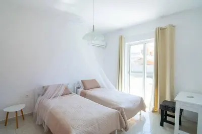 a white bedroom with two beds and a window at Fotis House 2 in Afantou