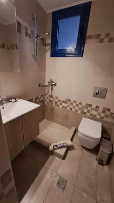 a bathroom with a sink and a toilet and a window at Déjà Blue in Archangelos