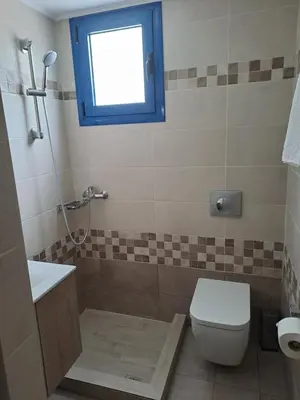a bathroom with a toilet and a sink and a window at Déjà Blue in Archangelos