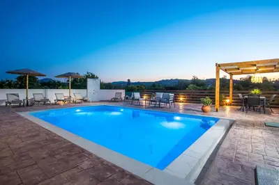 a swimming pool on a patio with chairs and umbrellas at Villa Merelia in Afantou