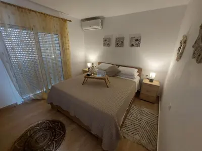 a bedroom with a bed with a table and a window at Afandou Square Apartment in Afantou