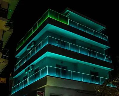 a building with green lights on it at night at Rodosrooms in Rhodes Town