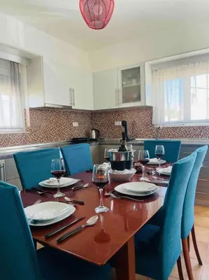 a wooden table with chairs and wine glasses on it at George House in Archangelos