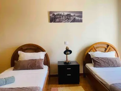 a bedroom with two beds and a lamp on a night stand at George House in Archangelos