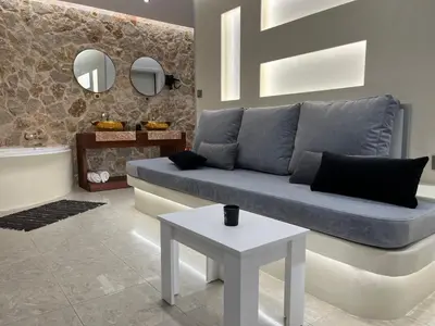 a living room with a blue couch and a table at 2-Luxury jacuzzi white suite by the sea in Rhodes Town