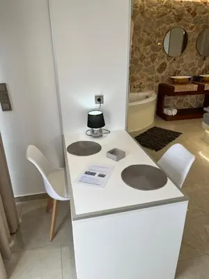 a kitchen with a white counter with a table and chairs at 2-Luxury jacuzzi white suite by the sea in Rhodes Town