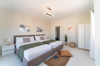 a white bedroom with a large bed and a rug at Emelia Cozy Apartment in Rhodes Town