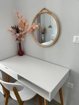 a white table with a mirror and a vase with flowers at Vixen Apartment Studio 2 in Theologos