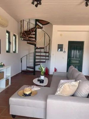 a living room with a couch and a spiral staircase at Villa Calliope Lardos in Lardos