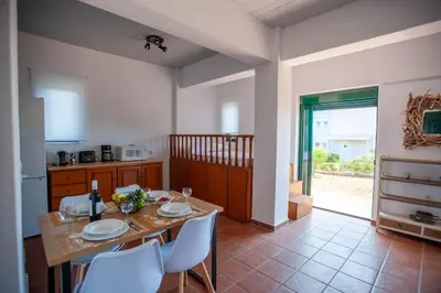 a kitchen with a table and white chairs and a table and a kitchen at Villa Calliope Lardos in Lardos