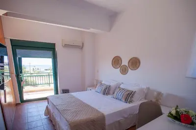 a white bedroom with a bed and a balcony at Villa Calliope Lardos in Lardos