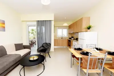 a living room with a couch and a table and a kitchen at Elli Garden View - Spacious Fully Equipped Apartment in Kremasti