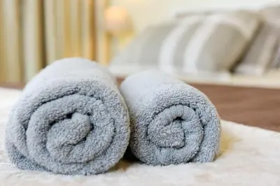 a pair of gray towels sitting on a bed at Elli Garden View - Spacious Fully Equipped Apartment in Kremasti