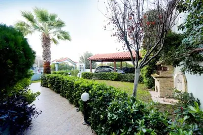 a garden with bushes and a house with a palm tree at Elli Garden View - Spacious Fully Equipped Apartment in Kremasti