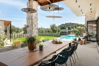 a patio with a wooden table and chairs and a pool at Mirena Luxury Living-Casa Di Ria in Afantou