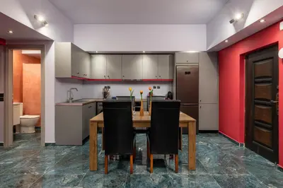 a kitchen with a wooden table and black chairs at Fata Morgana Apartment in Ialyssos