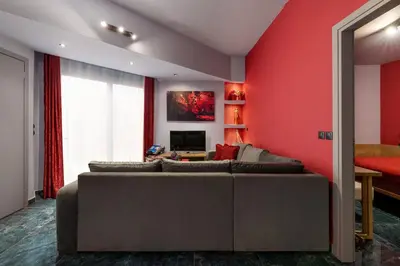 a living room with a couch and a red wall at Fata Morgana Apartment in Ialyssos