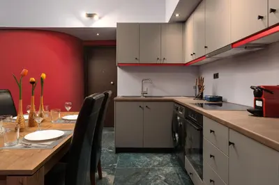 a kitchen with a wooden table and a red wall at Fata Morgana Apartment in Ialyssos