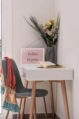 a white desk with a vase of flowers and a book at Villa Myrto in Ialyssos