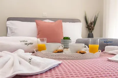 a breakfast table with orange juice and cookies on a bed at Villa Myrto in Ialyssos