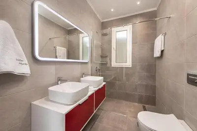 a bathroom with a white sink and a mirror at Villa Myrto in Ialyssos