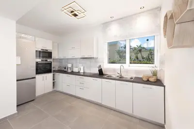 a white kitchen with white cabinets and a sink at Villa Myrto in Ialyssos