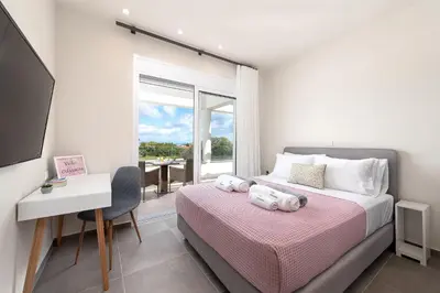 a bedroom with a bed with a desk and a window at Villa Odysseas in Ialyssos