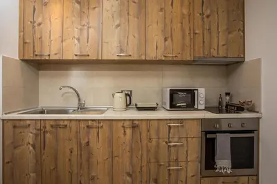 a kitchen with wooden cabinets and a sink and a microwave at M&E APARTMENTS in Haraki