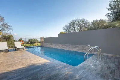 a swimming pool in a backyard with a wooden deck at City Art Villa in Asgourou