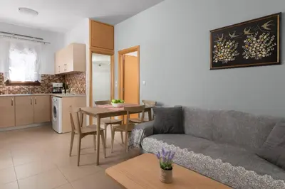 a living room with a couch and a table and a kitchen at gefiraki apartment in Koskinou