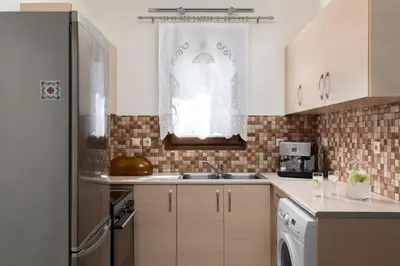 a kitchen with a sink and a refrigerator at gefiraki apartment in Koskinou