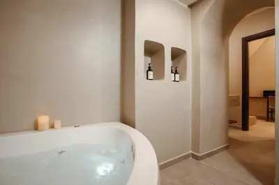 a bath tub in a bathroom with two candles at Noema Lindos - Athena Apartment in Líndos