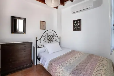 a white bedroom with a bed and a dresser at Genovefa traditional house in Koskinou