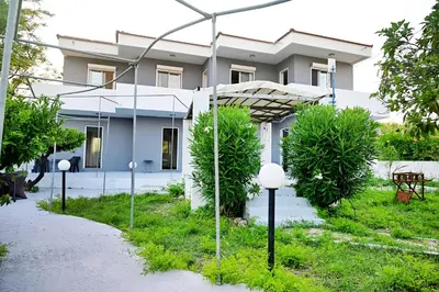a white house with trees in front of it at Karmik Concept Apartments in Afantou