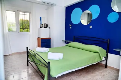 a bedroom with a green bed with a blue wall at Karmik Concept Apartments in Afantou