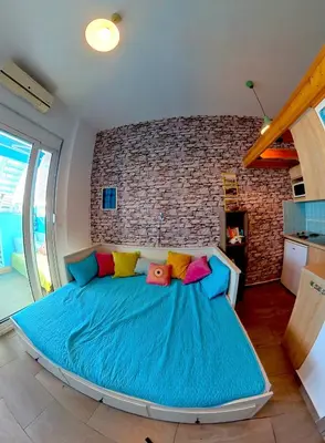 a bedroom with a large blue bed with colorful pillows at Beach Studio - Sleeps 2 & Private Ocean Terrace in Haraki