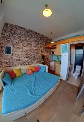 a large bed in a room with a brick wall at Beach Studio - Sleeps 2 & Private Ocean Terrace in Haraki
