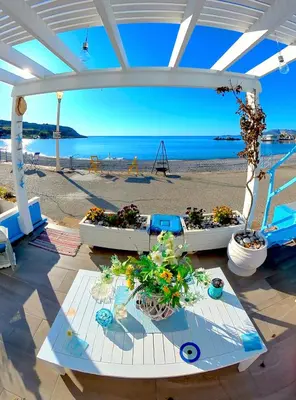 a patio with a table with flowers on a beach at Beach Studio - Sleeps 2 & Private Ocean Terrace in Haraki