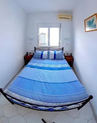a bedroom with a large bed with blue sheets at Deluxe Beach Apartment- Sleeps 2 & Private Terrace in Haraki