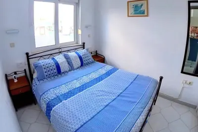 a blue bed in a white room with a window at Deluxe Beach Apartment- Sleeps 2 & Private Terrace in Haraki