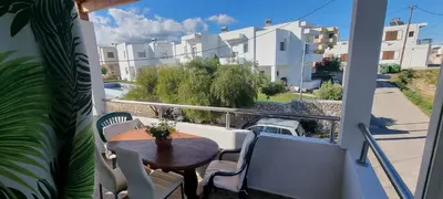 a balcony with a table and chairs and a view of buildings at A&J Apartments in Gennadi